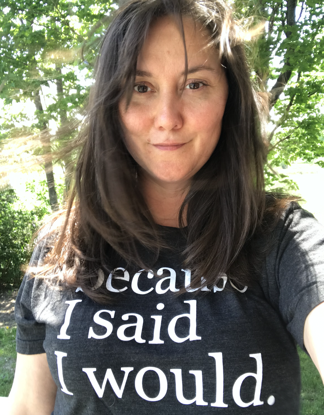 Eileen MacDonell smiling outdoors in the sun, wearing her “Because I said I would” t-shirt